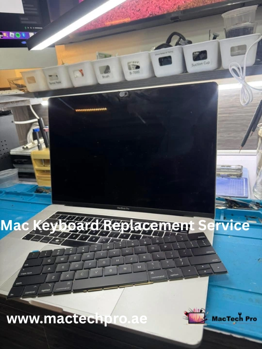 Keyboard flex connector micro-soldering under a microscope on a MacBook logic board in Dubai — MacTech Pro